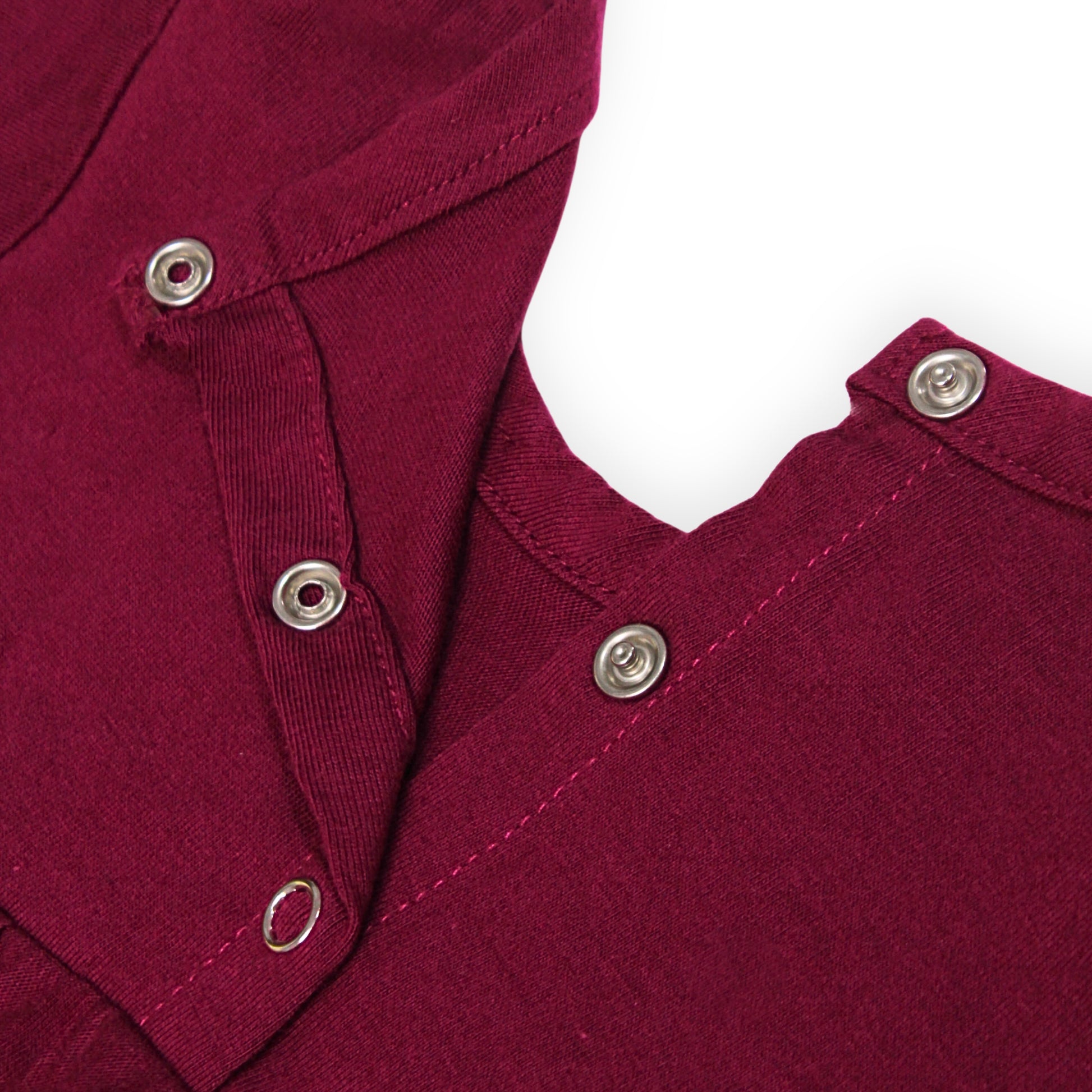 Close-up of a Babydrip Magenta Tunic Blouse neckline with silver metal snap open and shut buttons along the neckline, shown laying flat against a white background.