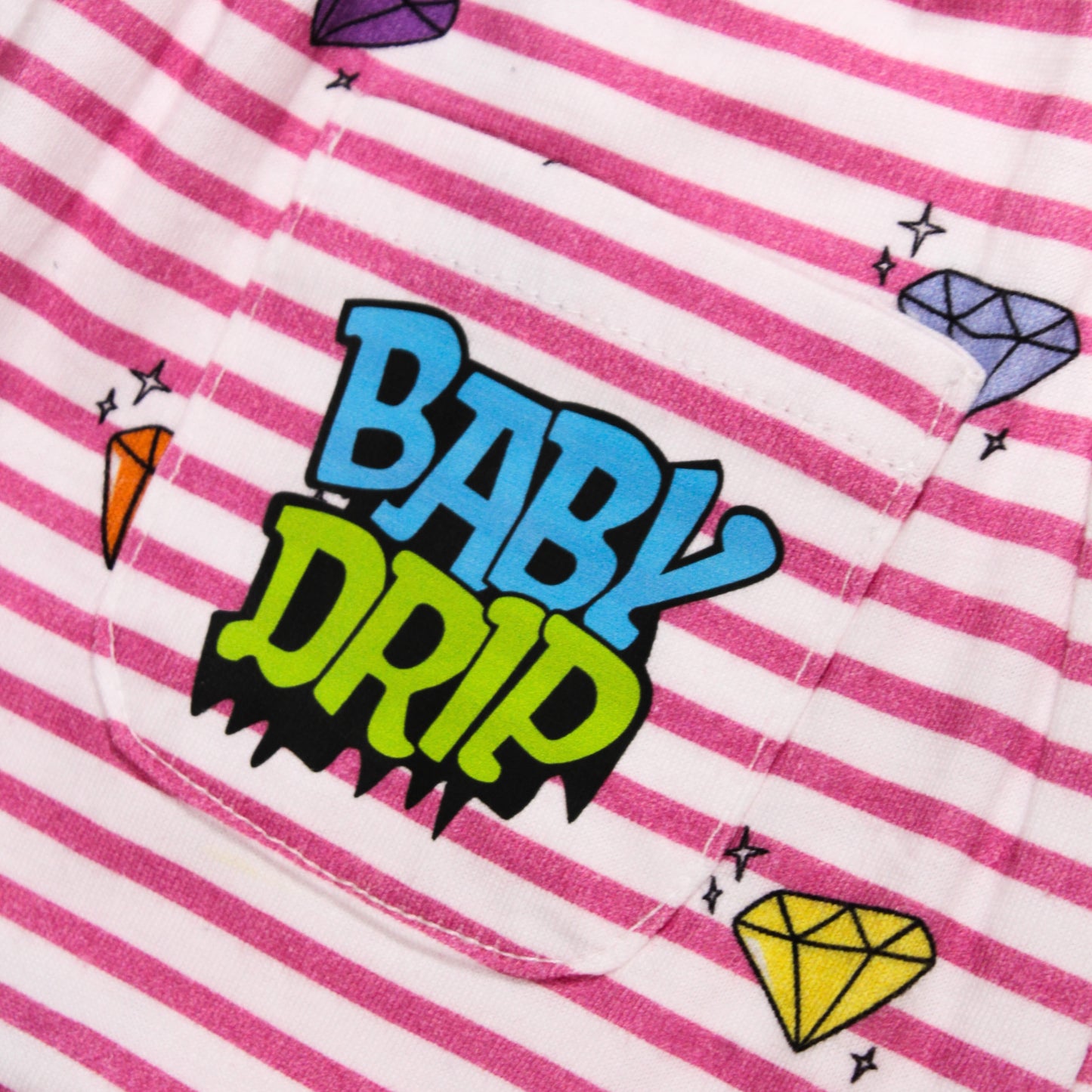 Close-up image of a Babydrip Pink  and white striped garment featuring a back pocket with a colorful 'BABY DRIP' Logo graphic and small diamond motifs illustrations around the pocket of the fabric.