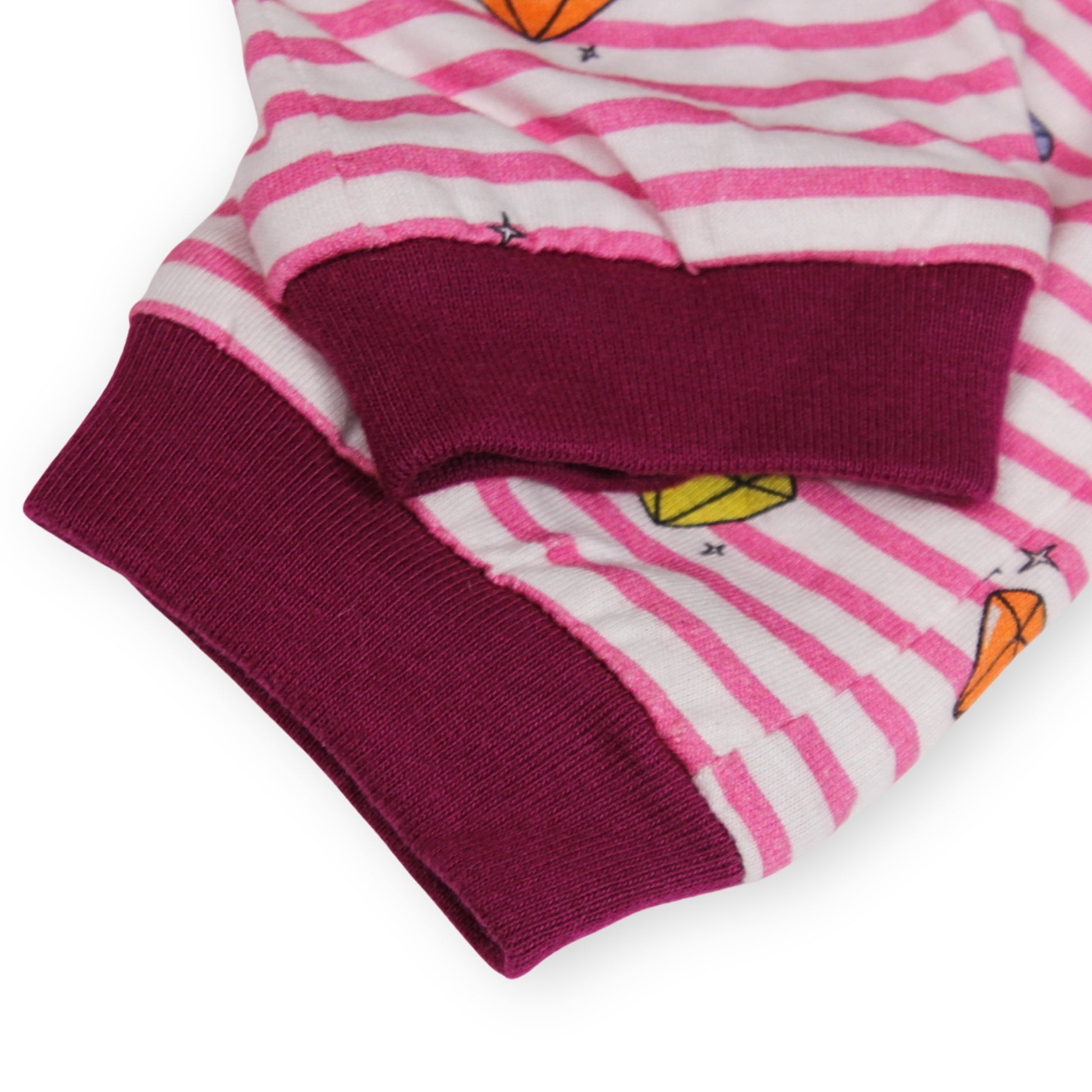 Close-up of a Babydrip Pants cuff. Featuring magenta colored ribbed cuffs and pink and white stripes, and small multicolor diamond graphic prints, laid out on a white background.