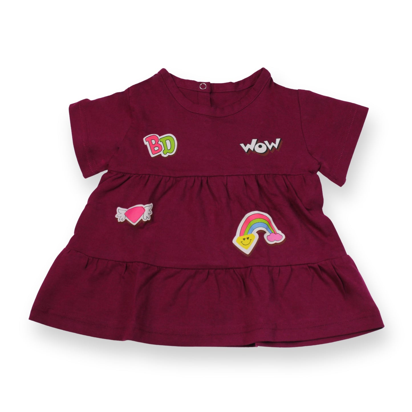 A Babydrip magenta short-sleeve tunic blouse with ruffled tiers, featuring embroidered patches including 'BabyDrip', (BD) 'WOW', a pink heart with angel wings, and a rainbow on a white background. Laid out flat on a white background.