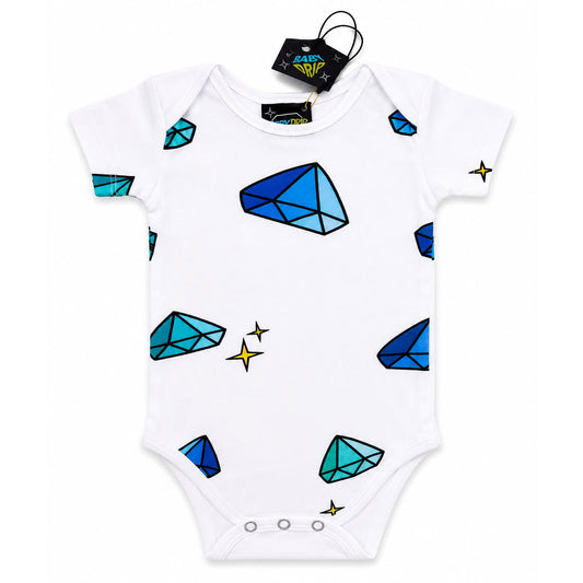 A babydrip white short-sleeve baby bodysuit onesie featuring a playful print of blue and teal diamonds and small yellow sparkles, with safety snap button closure at the bottom of the onesie. The onesie is shown laid flat on a white background with its black hangtag attached to the inside of the neck rim.