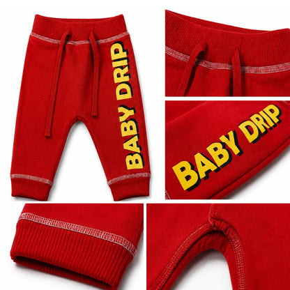 Babydrip Red 0-12 months jogger pants shown in a five-panel collage, featuring a full view, of the front of the pants with yellow text that reads "BABYDRIP" on the right leg of the pants in  the first panel. Close-up of the waistband and drawstrings, with white outer stitch in the second panel. Whilst the third panel shows a closeup of the 'BABY DRIP' text graphic on the right leg. The fourth panel showcases the inner legs of the center section of the pants whilst the fifth panel showcases the ribbed cuffs.