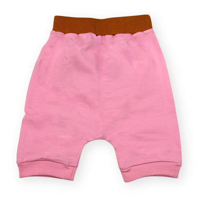 A Babydrip girls sweat shorts Image showing the back of the Pink terry cotton shorts with a brown elastic waistband and pink ribbed cuffs, laid flat on a white background.