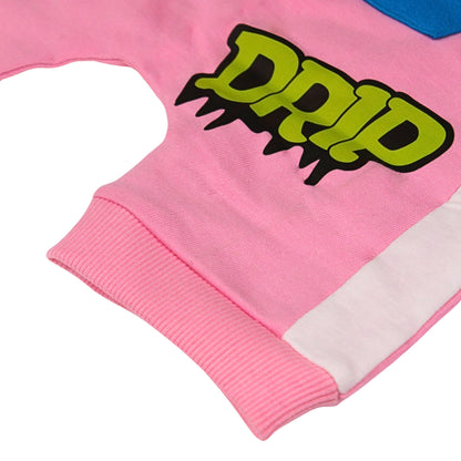 A Babydrip pink sweat short front cropped close-up image showing a pink ribbed cuff, a white side panel, and a large neon yellow-green text 'DRIP' graphic with black outline near to the lower section of the shorts, laid out flat on a white background.