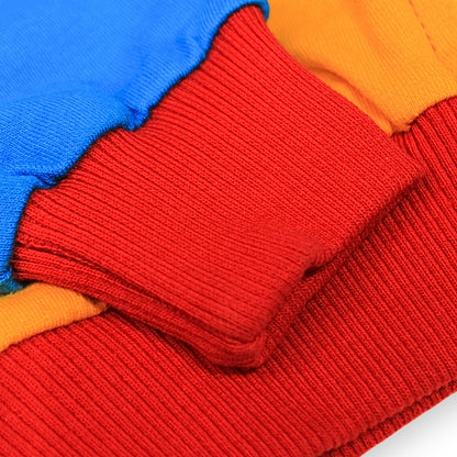 Babydrip close-up image of a folded knit sweater showing a red ribbed cuff and hem layered over bright blue and orange fabric.