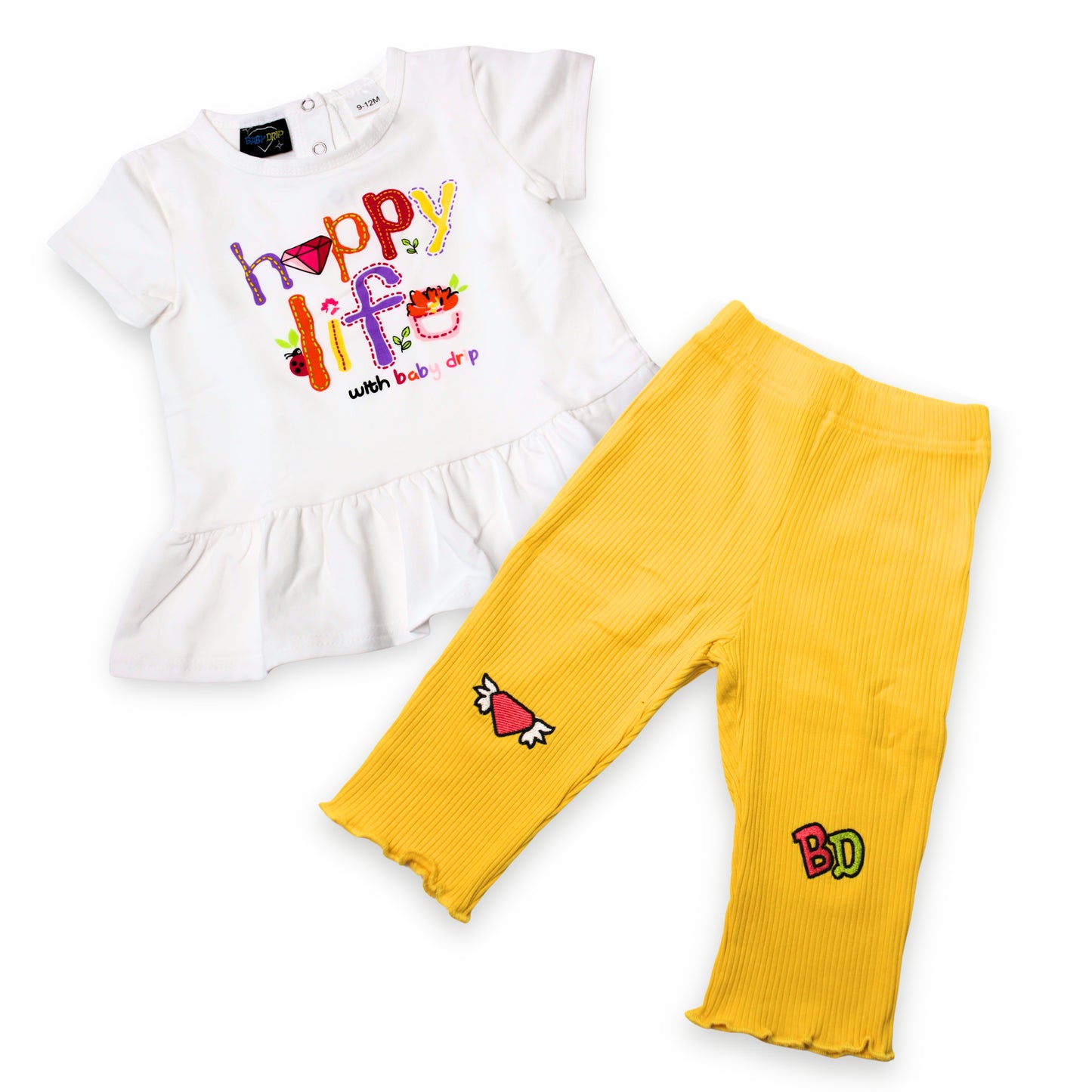 Babydrip girls 2-piece outfit featuring a white short-sleeve peplum top with a colorful 'Happy Life' graphic and yellow ribbed leggings with embroidered patches on a white background.