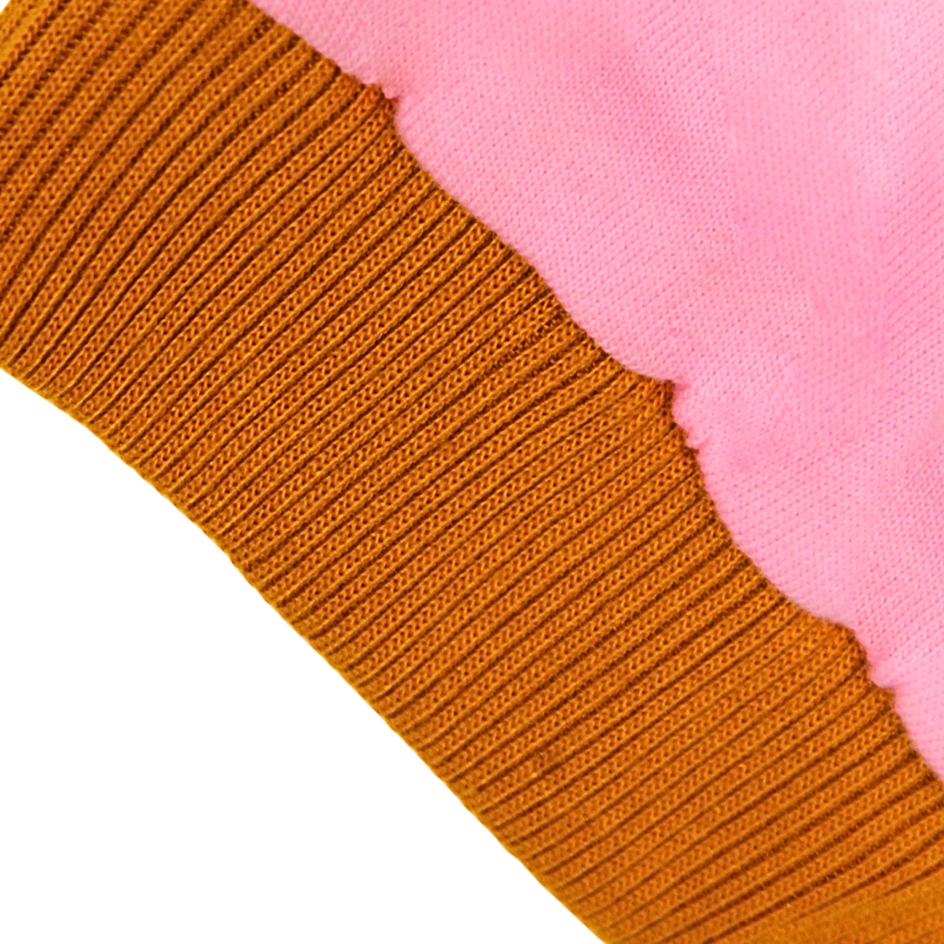 Close-up of a pink terry cotton knit fabric showing a ribbed brown cuff or trim layered over a soft pink plush or fleece section on a white background.